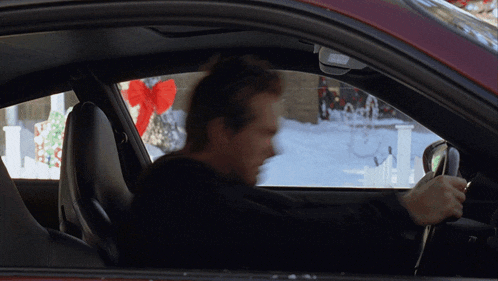 a man is driving a car with a red bow on the window