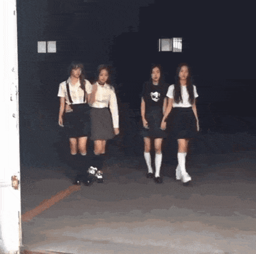 a group of girls in school uniforms are walking down a street .