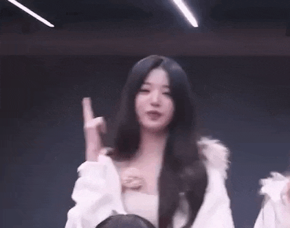 a woman with long hair is dancing in a dark room while wearing a white jacket .