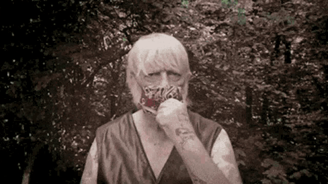 a man with a beard and a tattoo on his arm is eating a piece of meat
