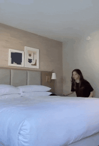 a woman is laying on a bed in a hotel room with three paintings on the wall
