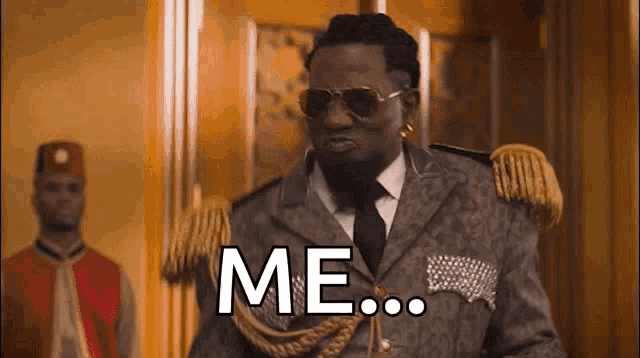 a man in a suit and tie is standing in a hallway and says me .