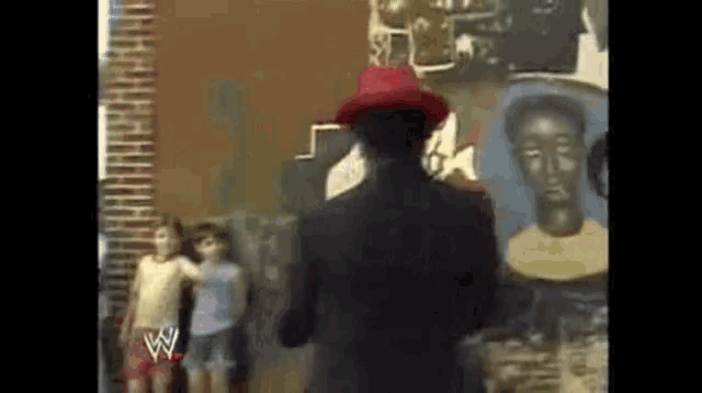 a man in a red hat is standing in front of a wall with a w on it