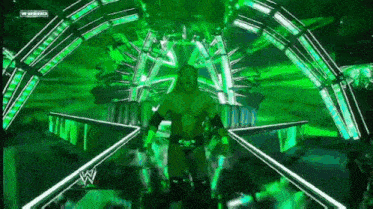 a wrestler is walking through a green tunnel with a wwe logo in the corner