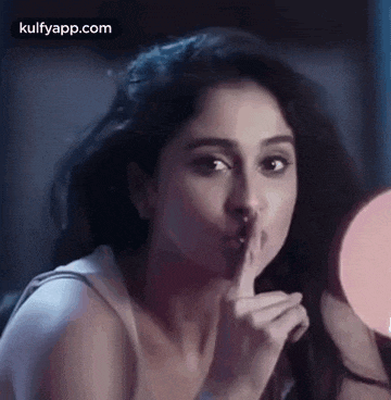 a woman is making a shhh gesture with her finger to her lips .