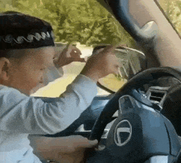 a young boy wearing a hat is driving a car .