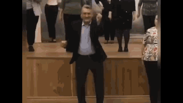 a man in a suit is dancing with a group of people on a stage .