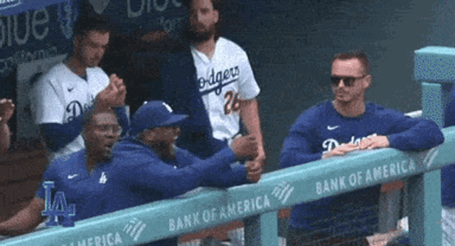 a group of baseball players wearing dodgers jerseys are sitting in a dugout