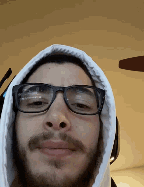 a man wearing glasses and a white hoodie is smiling
