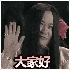 a woman with long hair and a flower in her hair is waving at the camera .