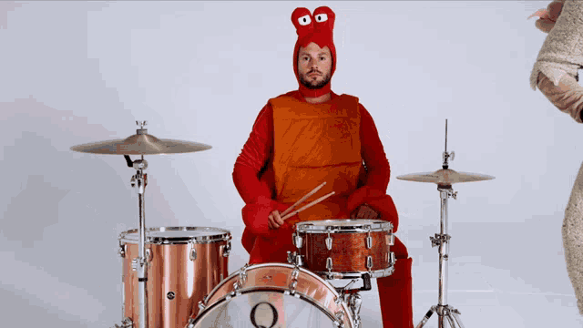 a man dressed as a lobster is playing drums