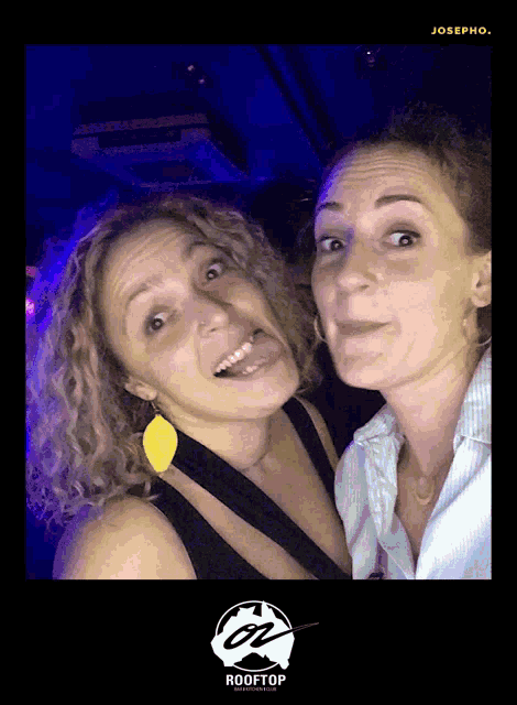 two women are posing for a photo with a rooftop logo on the bottom