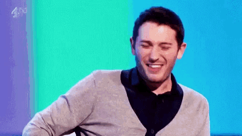 a man in a grey cardigan is smiling in front of a blue background that says 4hd on it