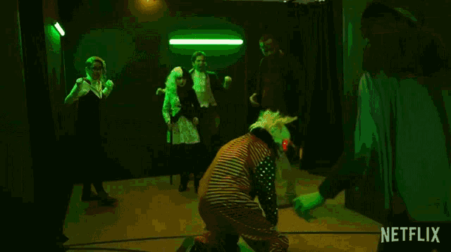 a man in a striped shirt is kicking another man in the face in a dark room .