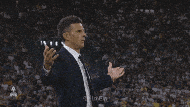 a man in a suit and tie is giving a thumbs up in front of a crowd ..