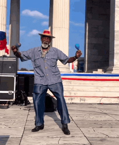 a man in a hat is dancing with maracas in front of a building