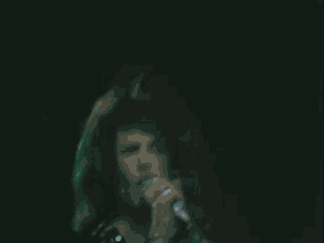 a woman is singing into a microphone in the dark