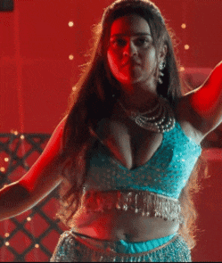 a woman in a blue top is dancing in a dark room .