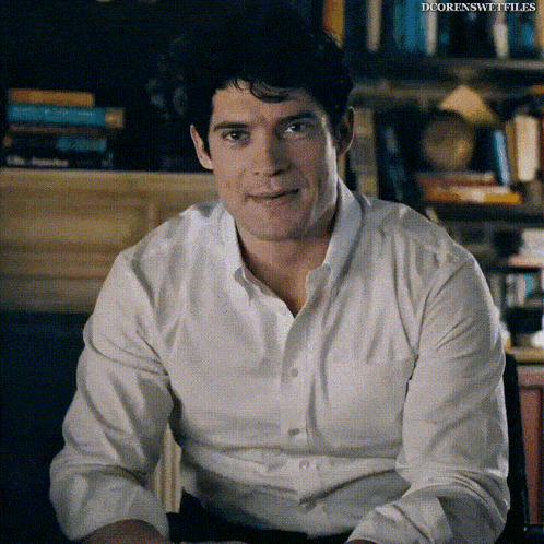 a man in a white shirt is smiling and looking at the camera