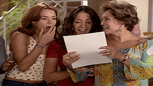three women are laughing while one holds a piece of paper