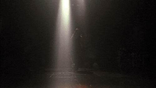 a person standing in a dark room with a spotlight shining on them