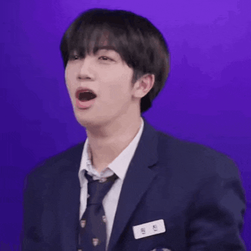 a young man in a suit and tie is making a funny face with his mouth open .