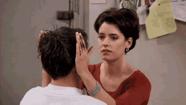 a woman is touching a man 's head with her hand
