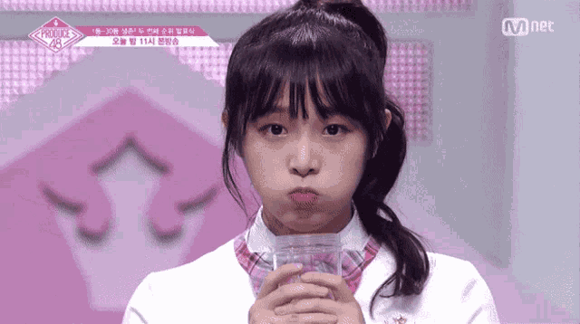 a girl is making a funny face while holding a glass of water .