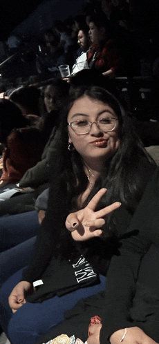 a woman giving a peace sign while wearing a shirt that says ' nyc ' on it