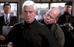 a group of men are standing next to each other in a room and one of them is holding another man 's arm .