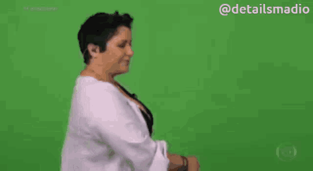 a woman is standing in front of a green screen and pointing .