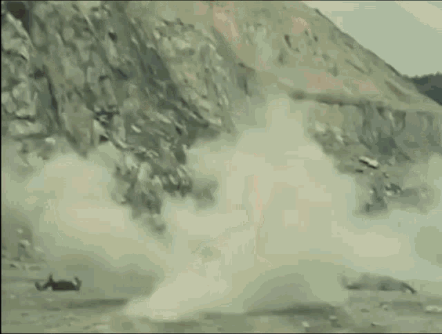 a man in a pink superhero costume is standing in front of a rocky hill .