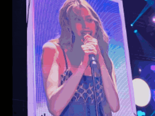 a woman singing into a microphone with a purple background