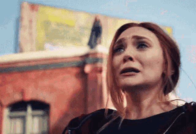 a woman is crying in front of a building with a billboard in the background .