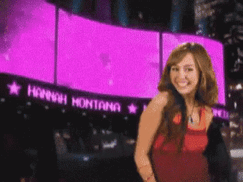 hannah montana is standing in front of a large purple screen