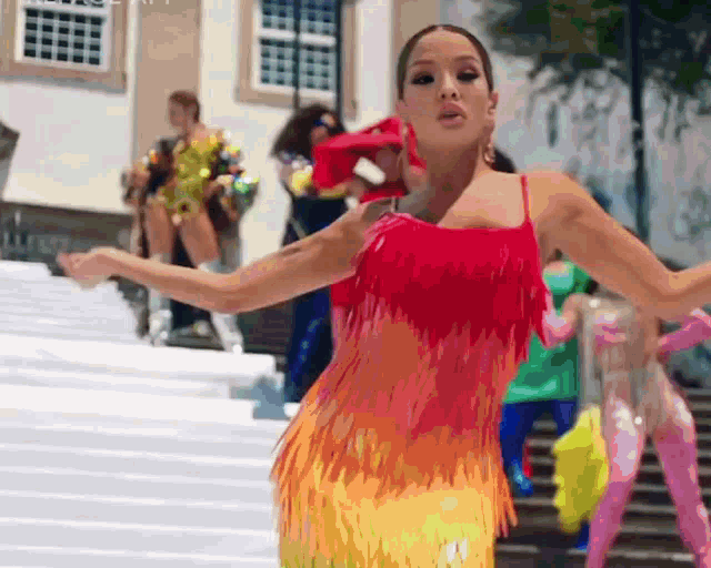 a woman in a red fringed dress is dancing on stairs