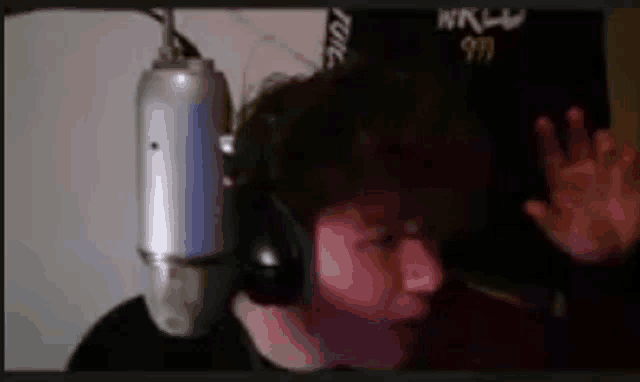 a man wearing headphones and a microphone is waving his hand