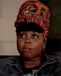 a woman wearing a head scarf and a denim jacket is making a serious face