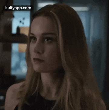 a close up of a woman 's face with long blonde hair and a serious look on her face .