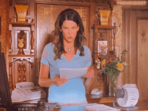 a woman in a blue shirt is holding a piece of paper with the word trendizisst on the bottom