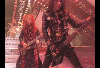 a couple of people playing guitars on stage