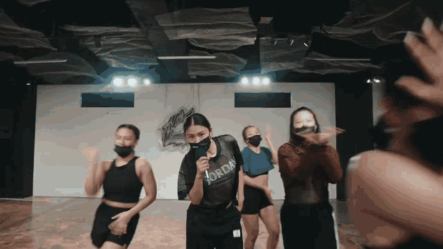 a woman wearing a jordan shirt is singing into a microphone while dancing