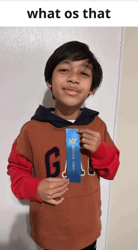 a young boy wearing a gap sweatshirt holds up a blue ribbon