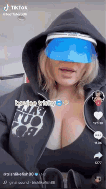 a woman wearing a hoodie and a blue visor is a tiktok video .