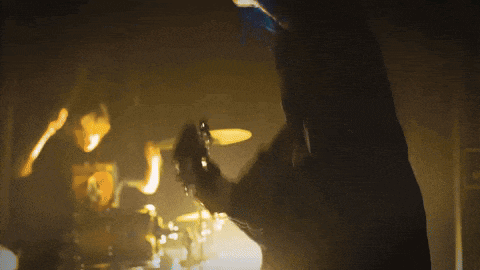 a man playing drums in a dark room with smoke coming out of his mouth