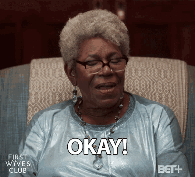 a woman sitting in a chair with okay written on her chest