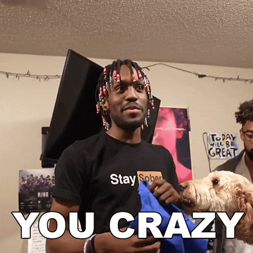 a man wearing a black shirt that says " stay sober " holds a dog and says " you crazy "