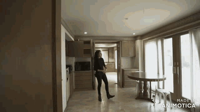 a woman is dancing in an empty room with the words made in animatica on the bottom