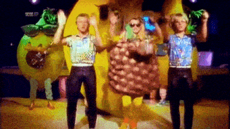 a group of people dressed in fruit costumes are dancing on a stage .