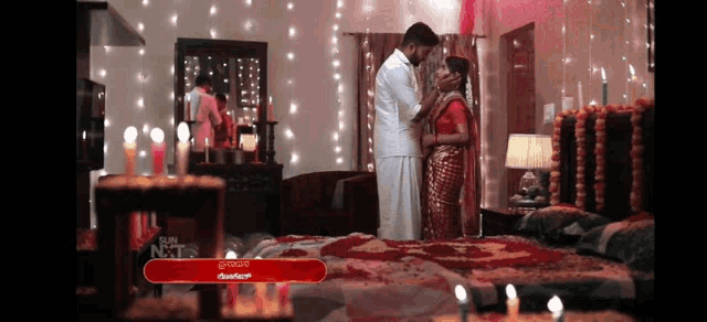 a man and a woman are kissing in a bedroom decorated with candles and flowers .